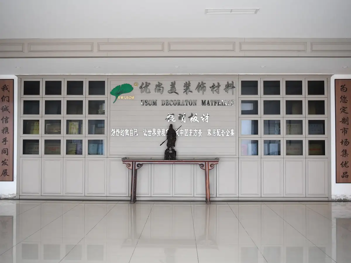 锟明板材公司前台形象墙,中央为优尚美装饰材料与锟明板材标识,两侧为诚信经营主题的木质对联